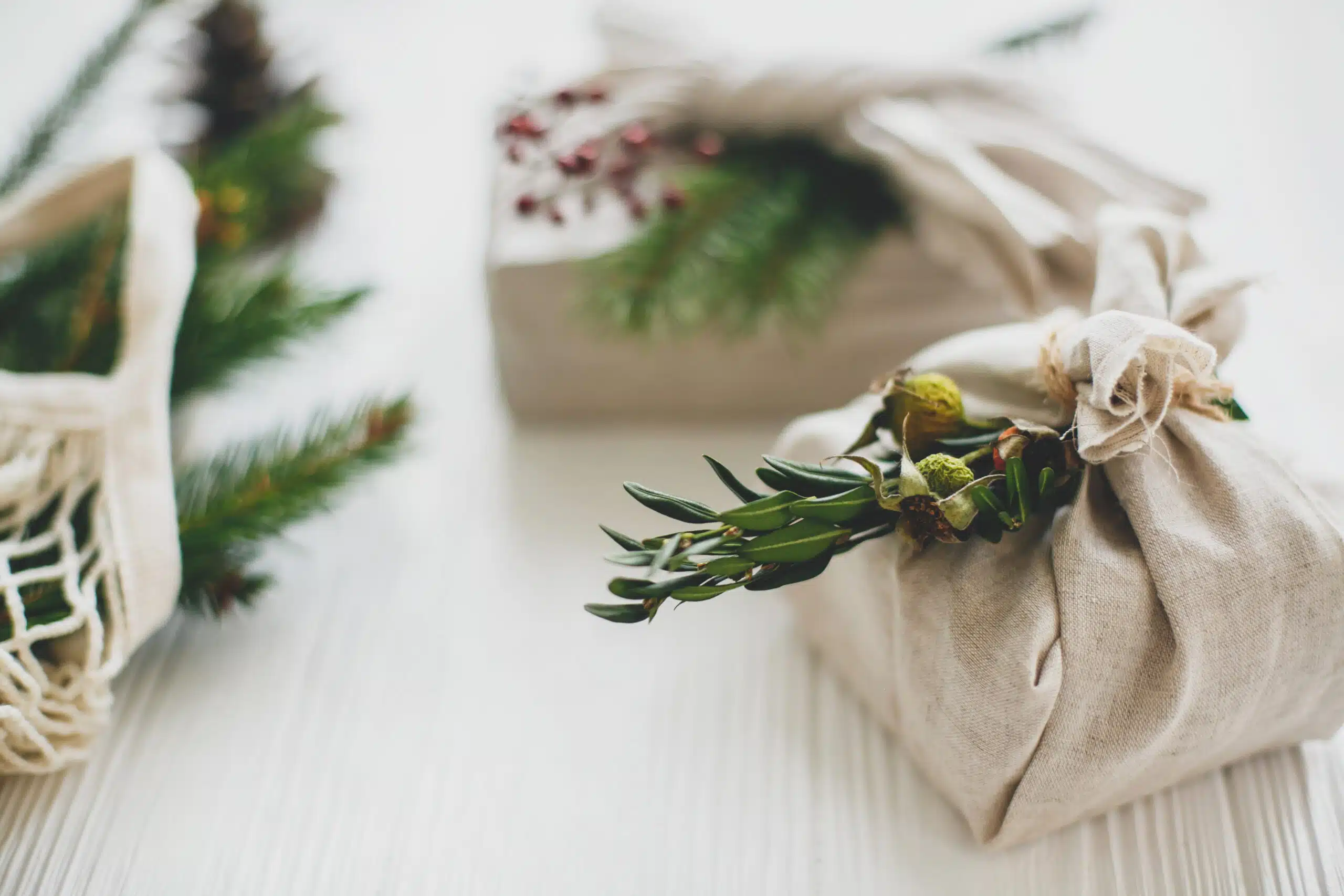 Stylish christmas gifts wrapped in linen fabric with green branch
